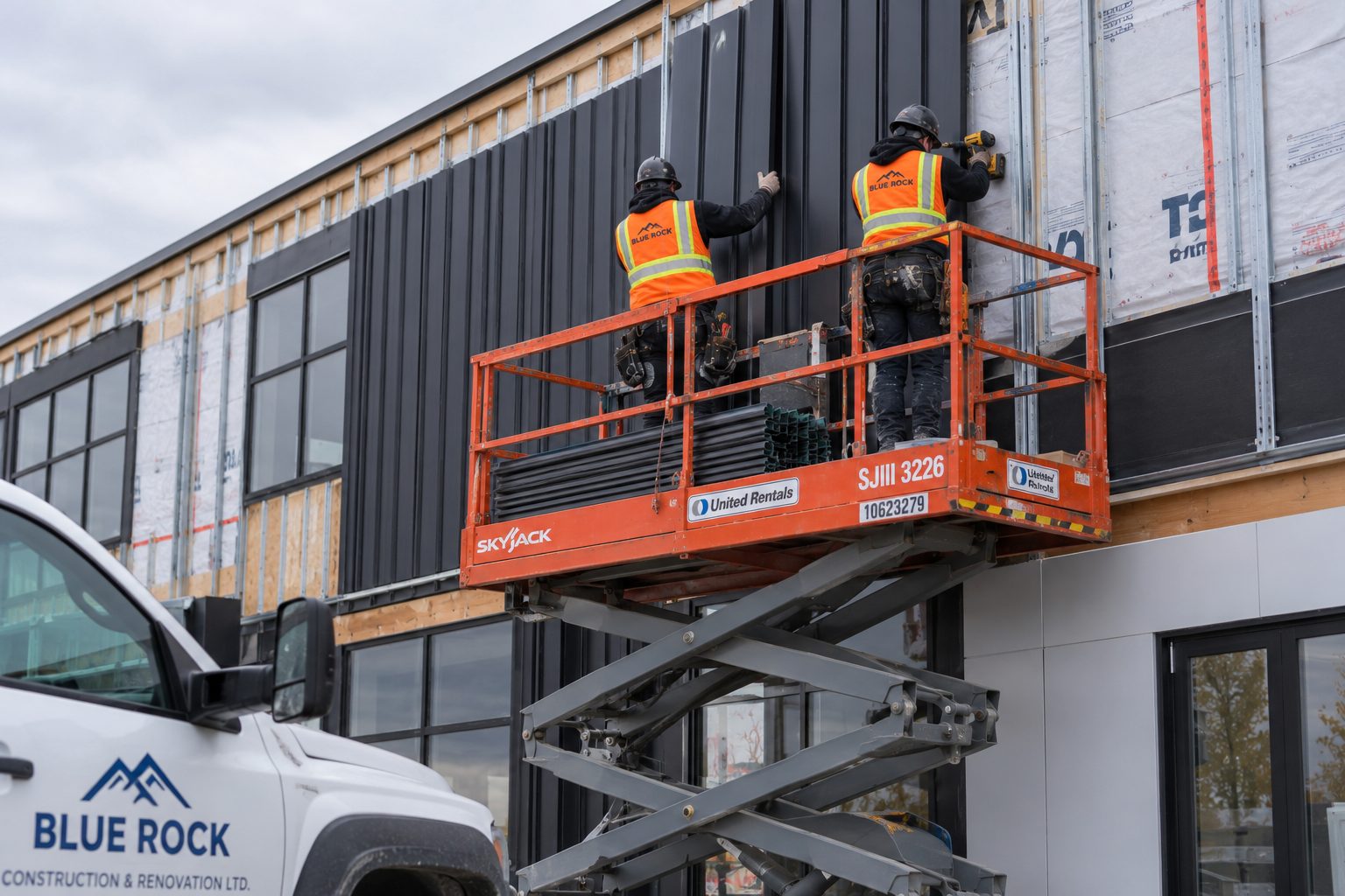 Partner crew installing metal cladding from a scissor lift